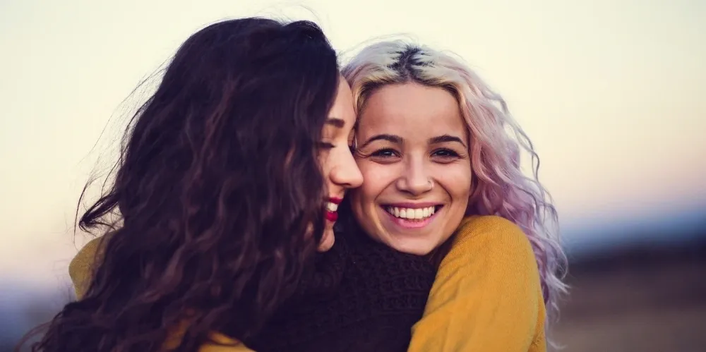 rs=w_1000,h_500,cg_true (2) Two women are hugging and smiling for the camera.
